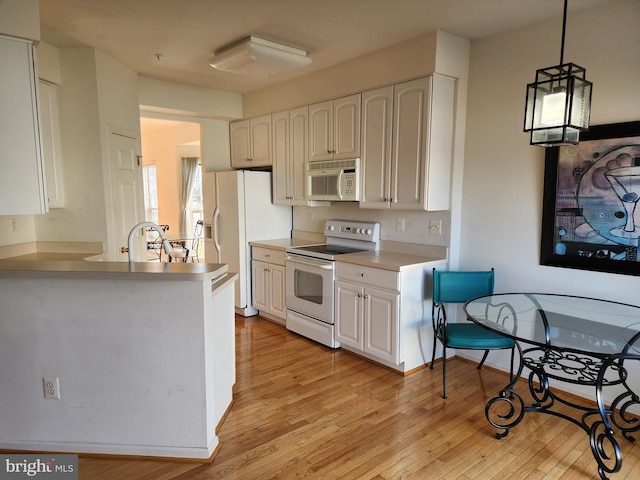 kitchen with white appliances, white cabinetry, light countertops, and light wood-style floors