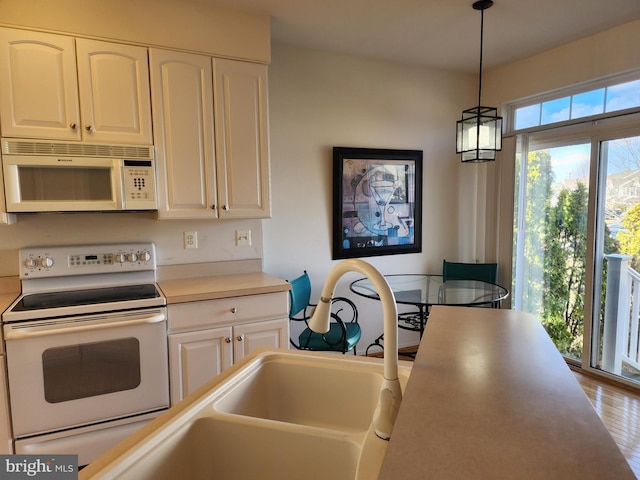 kitchen featuring hanging light fixtures, white appliances, white cabinetry, and light countertops