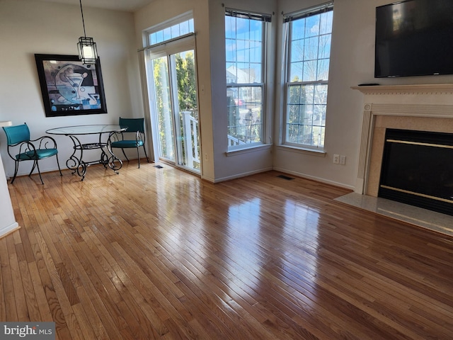 unfurnished living room with a fireplace with flush hearth, visible vents, baseboards, and hardwood / wood-style flooring