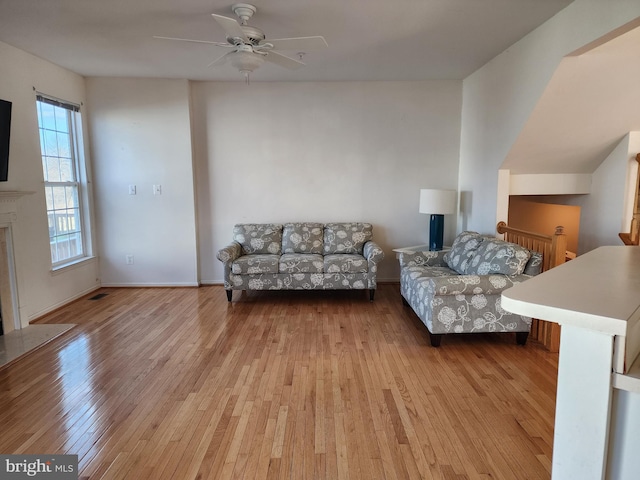 living room featuring visible vents, baseboards, hardwood / wood-style floors, a fireplace, and a ceiling fan