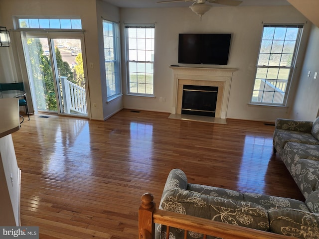 living room featuring visible vents, a ceiling fan, wood finished floors, a fireplace, and baseboards