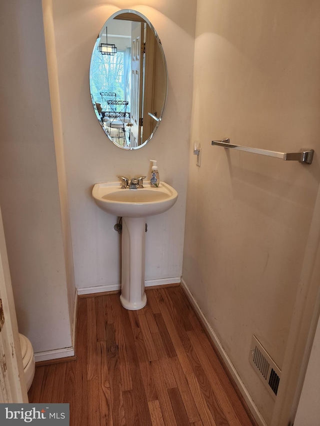 half bathroom featuring visible vents, toilet, baseboards, and wood finished floors