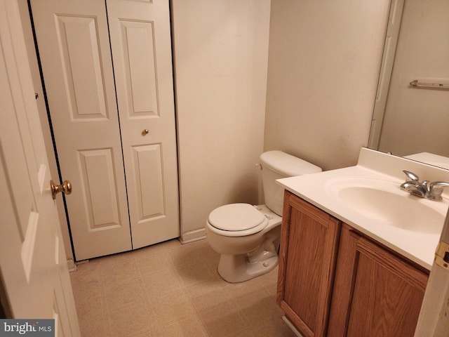 half bathroom with tile patterned floors, toilet, and vanity