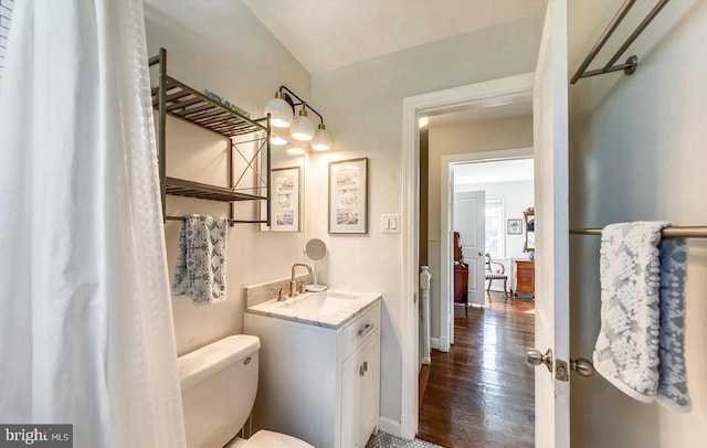 bathroom with baseboards, toilet, wood finished floors, and vanity