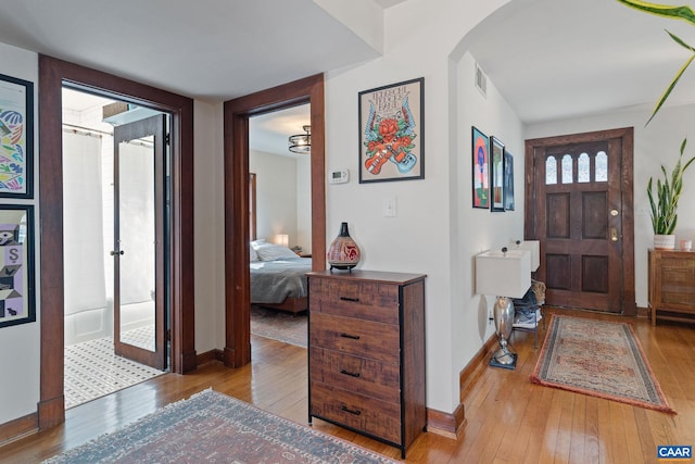 foyer entrance featuring arched walkways, visible vents, baseboards, and wood-type flooring