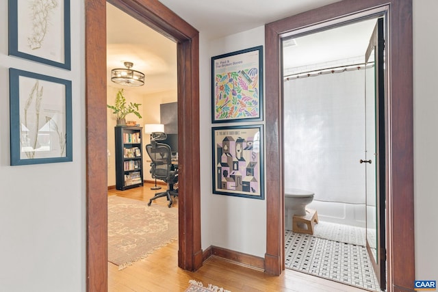 hall with baseboards and wood finished floors