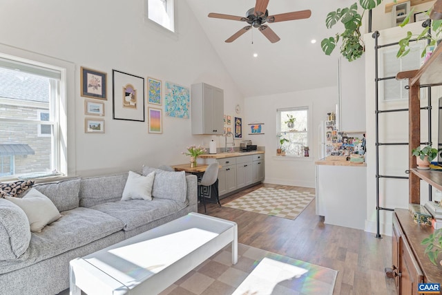 living area with baseboards, light wood finished floors, high vaulted ceiling, recessed lighting, and ceiling fan