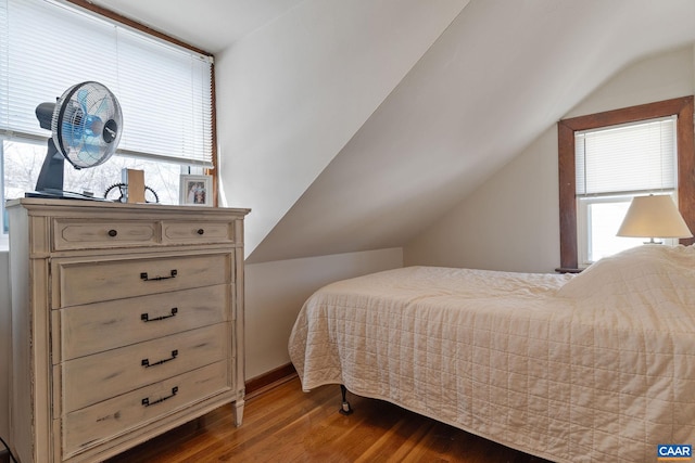 bedroom with multiple windows, lofted ceiling, and wood finished floors