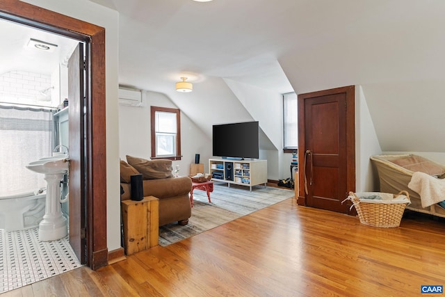 interior space with wood finished floors, vaulted ceiling, and a wall mounted AC