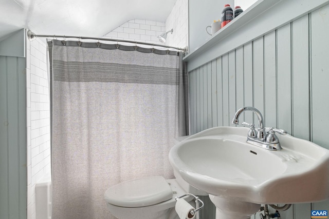 full bath featuring toilet, shower / bath combo with shower curtain, and a sink