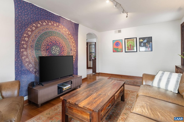 living area featuring visible vents, track lighting, wood finished floors, arched walkways, and baseboards