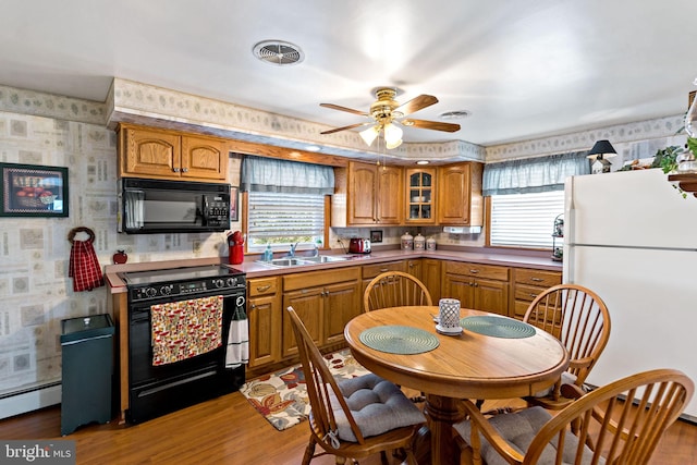 kitchen with brown cabinetry, visible vents, wallpapered walls, a sink, and black appliances