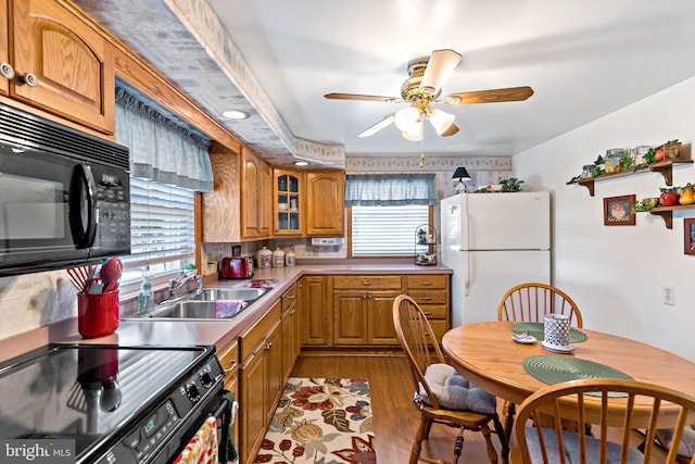 kitchen featuring brown cabinetry, black appliances, a wealth of natural light, and a sink