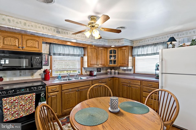 kitchen with visible vents, wallpapered walls, brown cabinetry, black appliances, and a sink