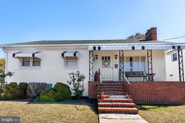 bungalow-style house featuring covered porch, a chimney, and roof with shingles