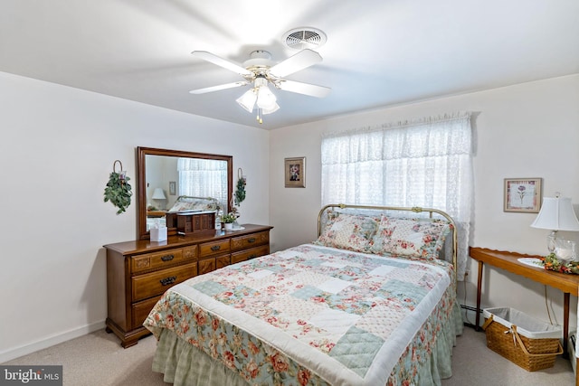 bedroom featuring visible vents, a baseboard heating unit, baseboards, ceiling fan, and light colored carpet