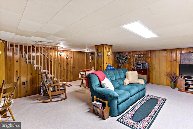 carpeted living area featuring wooden walls and stairs