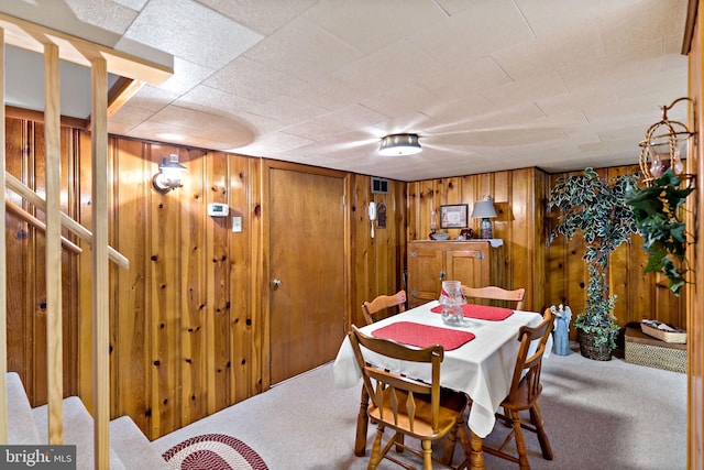 dining space featuring carpet flooring and wooden walls