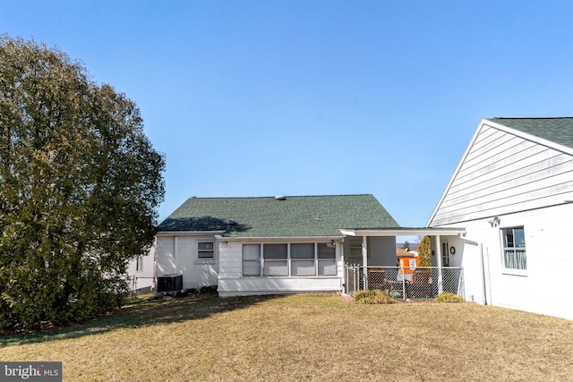 rear view of house featuring central air condition unit, a lawn, roof with shingles, and fence