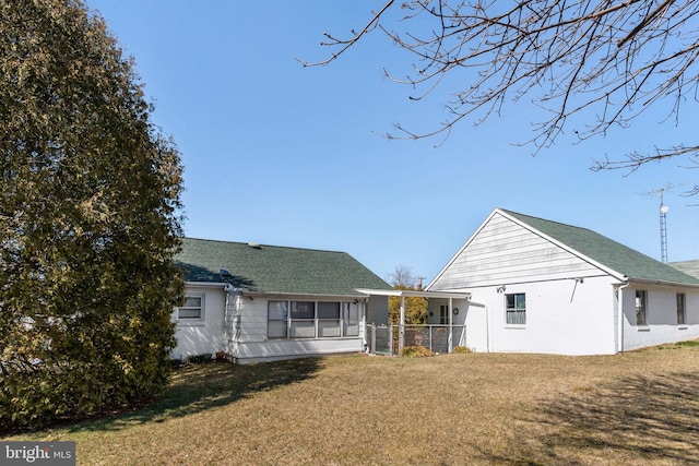 rear view of house featuring a yard and roof with shingles