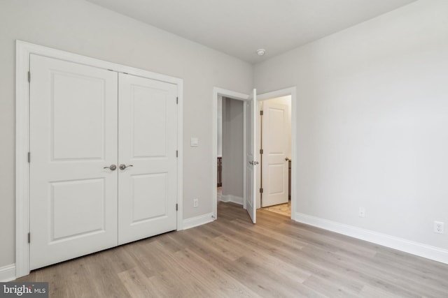 unfurnished bedroom featuring a closet, baseboards, and light wood finished floors