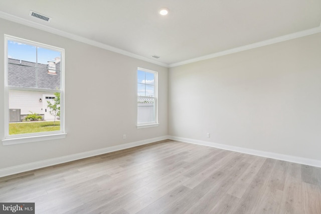 unfurnished room with visible vents, baseboards, light wood-style floors, and ornamental molding