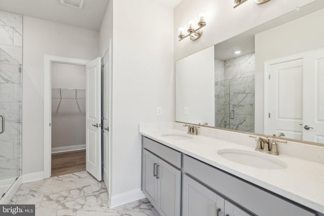 full bath with baseboards, marble finish floor, a marble finish shower, and a sink