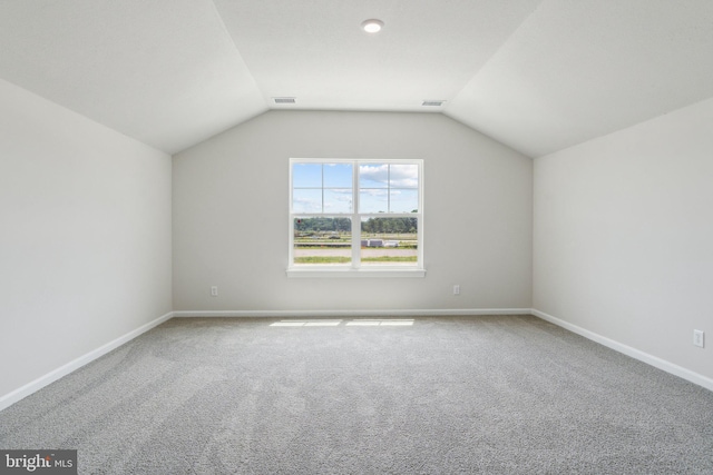 additional living space featuring baseboards, lofted ceiling, carpet floors, and visible vents