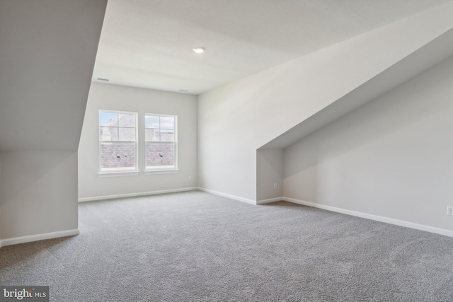 bonus room featuring lofted ceiling, carpet flooring, and baseboards