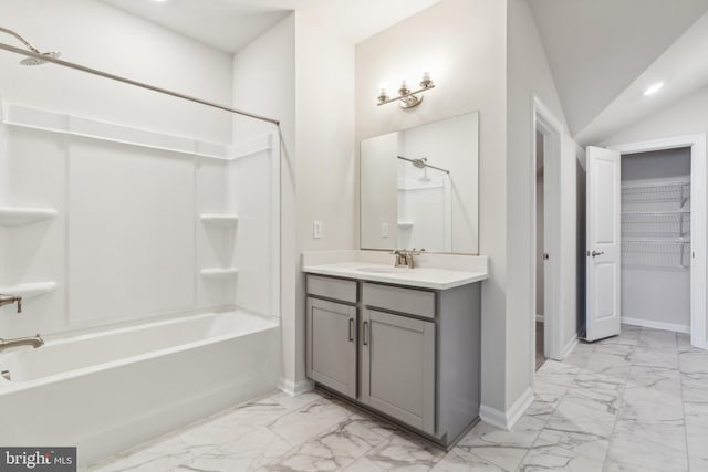 bathroom featuring baseboards, washtub / shower combination, lofted ceiling, marble finish floor, and vanity