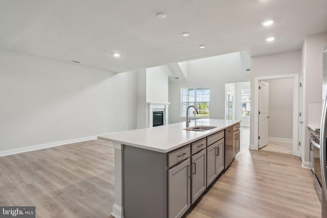 kitchen with gray cabinetry, a sink, open floor plan, a fireplace, and dishwasher