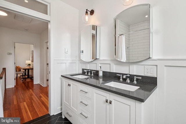 106 15th St SE, Washington, DC 20003 - bathroom featuring double vanity, a tile shower, a wainscoted wall, and a decorative wall