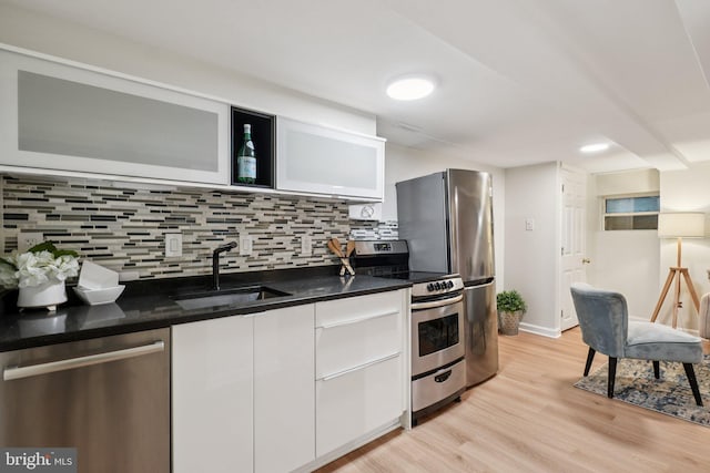 106 15th St SE, Washington, DC 20003 - kitchen featuring appliances with stainless steel finishes, light wood-style floors, decorative backsplash, white cabinetry, and modern cabinets