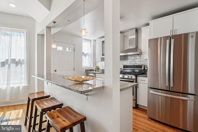 106 15th St SE, Washington, DC 20003 - kitchen with appliances with stainless steel finishes, wall chimney range hood, light wood-style flooring, a breakfast bar, and recessed lighting