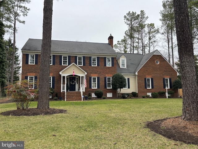 colonial-style house featuring crawl space, a front lawn, brick siding, and a chimney