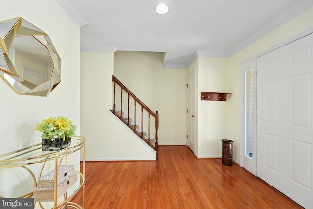 entryway featuring wood finished floors, baseboards, recessed lighting, ornamental molding, and stairs