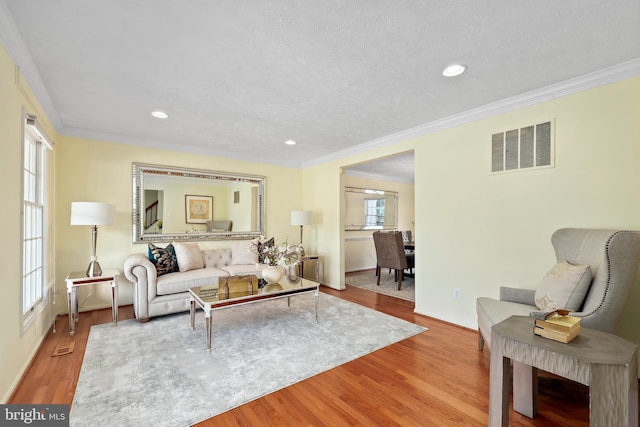 living room featuring recessed lighting, visible vents, wood finished floors, and ornamental molding