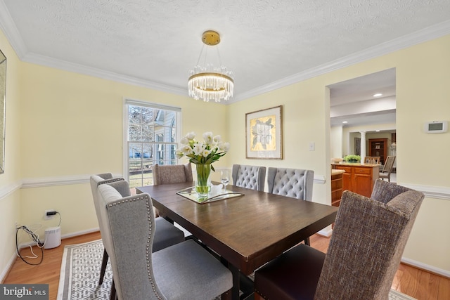 dining room with crown molding, light wood-style flooring, and a textured ceiling