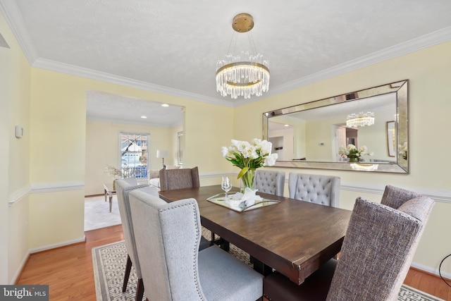 dining space with an inviting chandelier, wood finished floors, baseboards, and ornamental molding