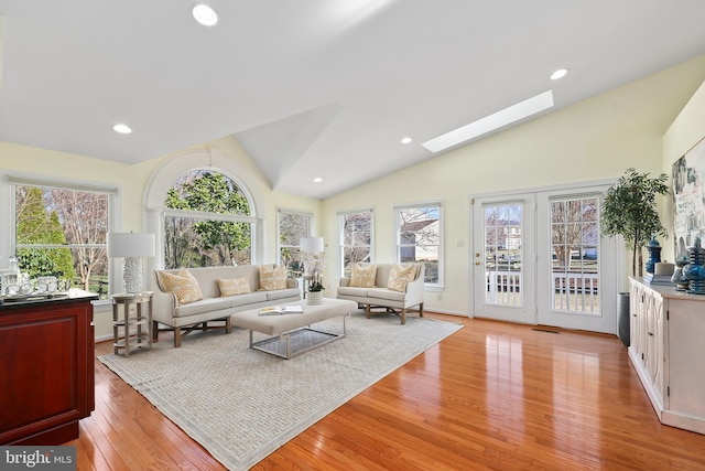 living area with recessed lighting, vaulted ceiling with skylight, and light wood-type flooring