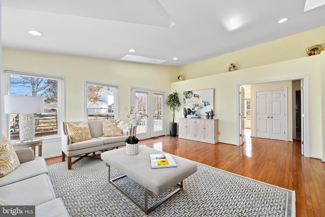 living area with recessed lighting, vaulted ceiling with skylight, french doors, and wood finished floors