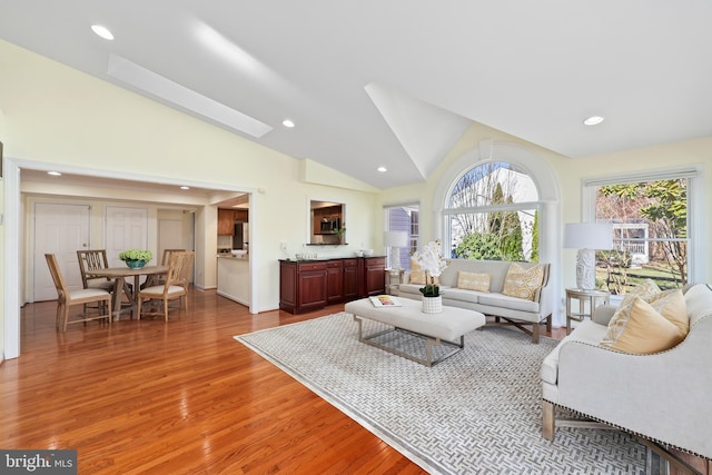 living area with recessed lighting, light wood-style floors, and high vaulted ceiling