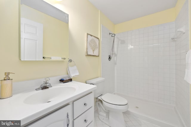 bathroom featuring vanity, toilet, tile patterned flooring, and a tile shower