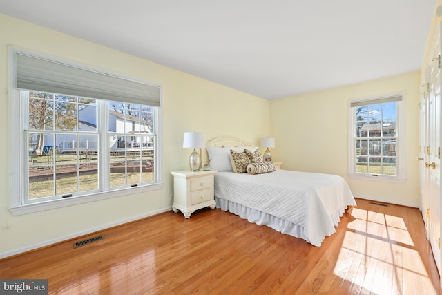 bedroom with light wood-type flooring, visible vents, and baseboards