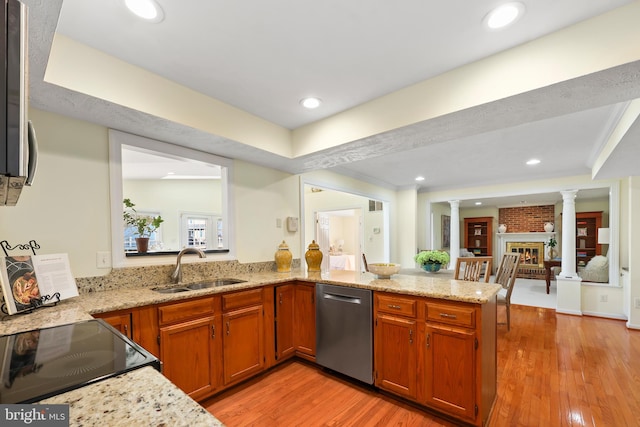 kitchen with a peninsula, decorative columns, a fireplace, a sink, and dishwasher