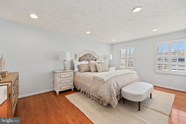 bedroom with recessed lighting, baseboards, a textured ceiling, and wood finished floors