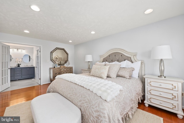 bedroom with recessed lighting, a textured ceiling, and wood finished floors