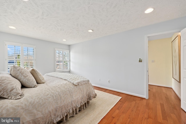 bedroom with recessed lighting, baseboards, a textured ceiling, and light wood finished floors