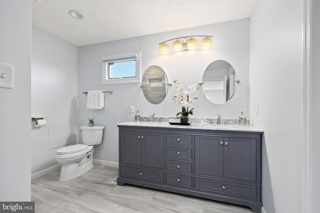 full bathroom featuring a sink, toilet, double vanity, and a textured ceiling