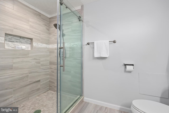 bathroom featuring toilet, baseboards, and a stall shower